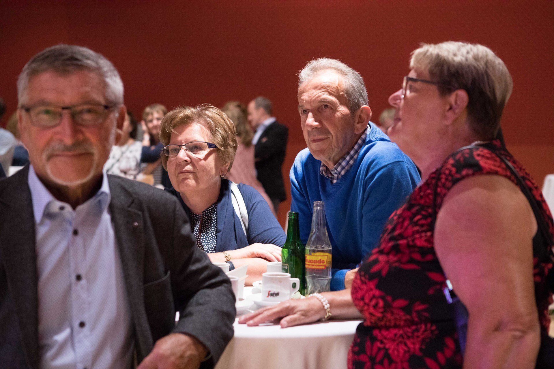 Eine Gruppe von Menschen sitzt in einem Raum an einem Tisch.