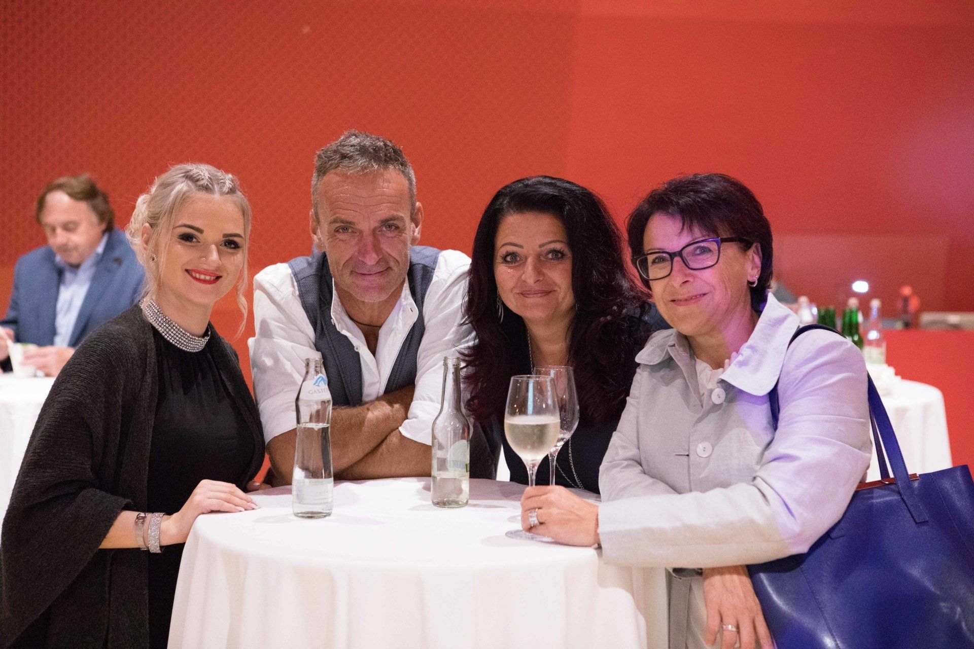 Eine Gruppe von Menschen sitzt mit Weingläsern an einem Tisch.