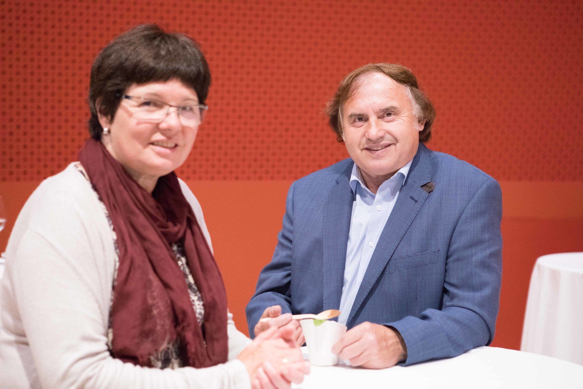 Ein Mann und eine Frau sitzen an einem Tisch und halten sich an den Händen.