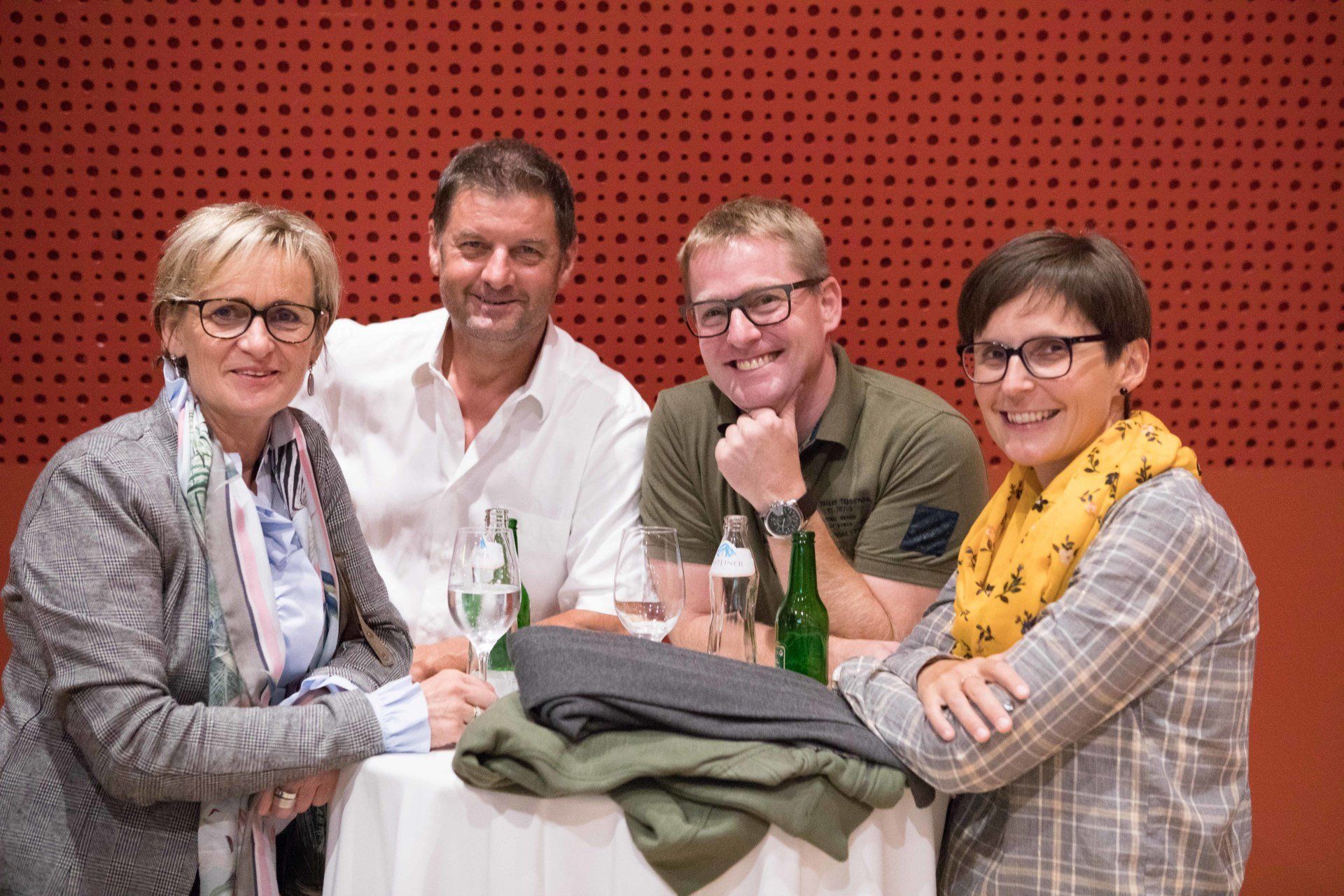 Eine Gruppe von Menschen sitzt mit Weingläsern an einem Tisch.