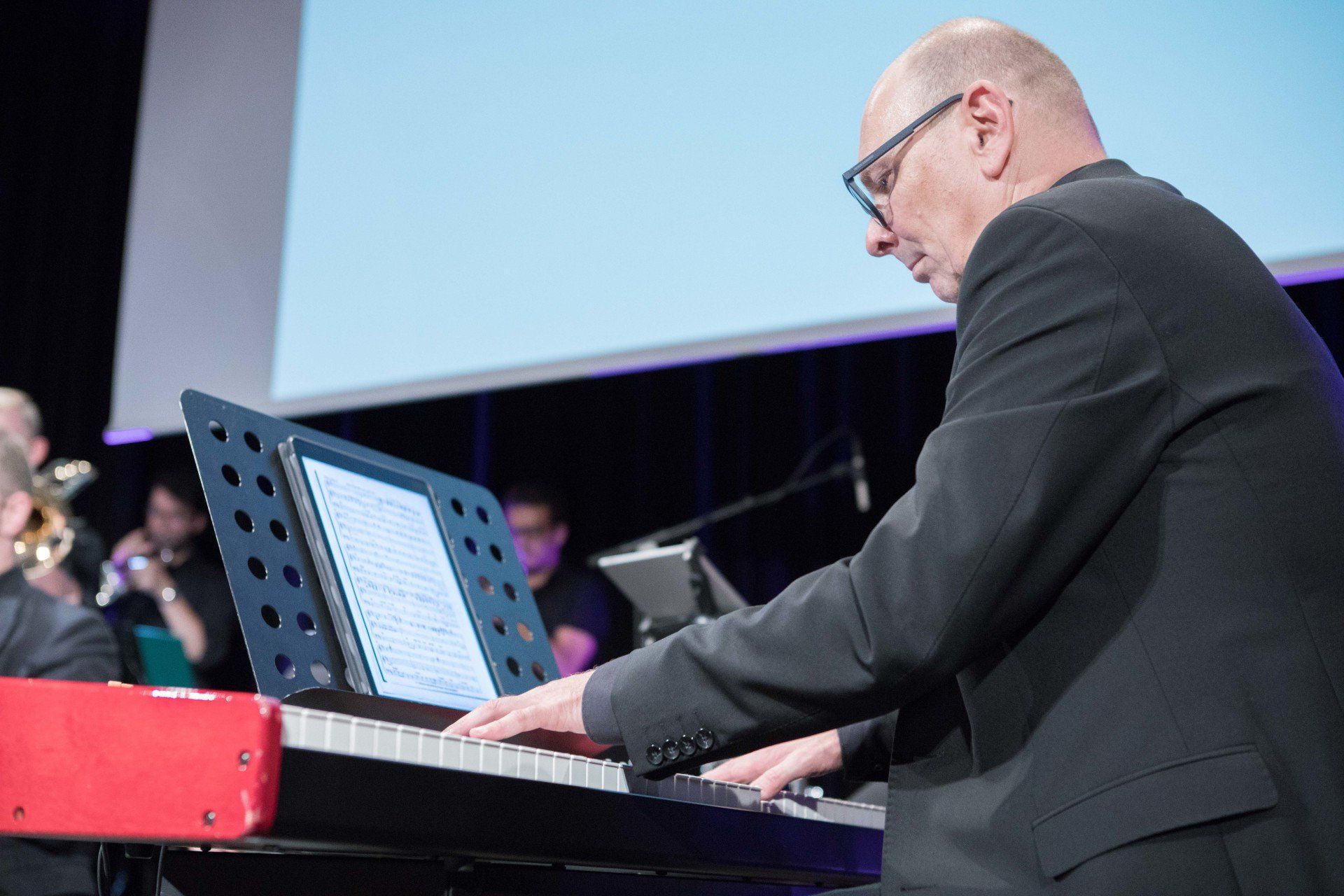 Ein Mann im Anzug spielt auf einer Bühne Keyboard.