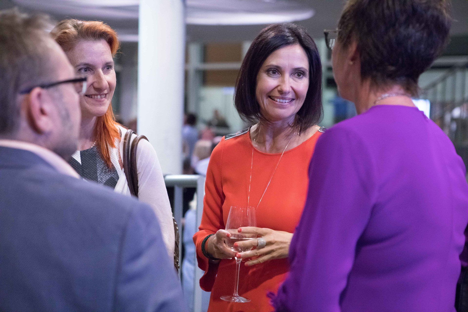 Eine Gruppe von Leuten steht in einem Raum herum und unterhält sich.