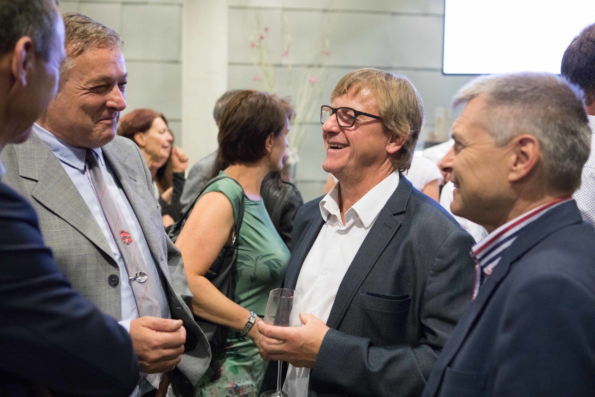 Eine Gruppe von Männern in Anzug und Krawatte unterhält sich in einem Raum miteinander.