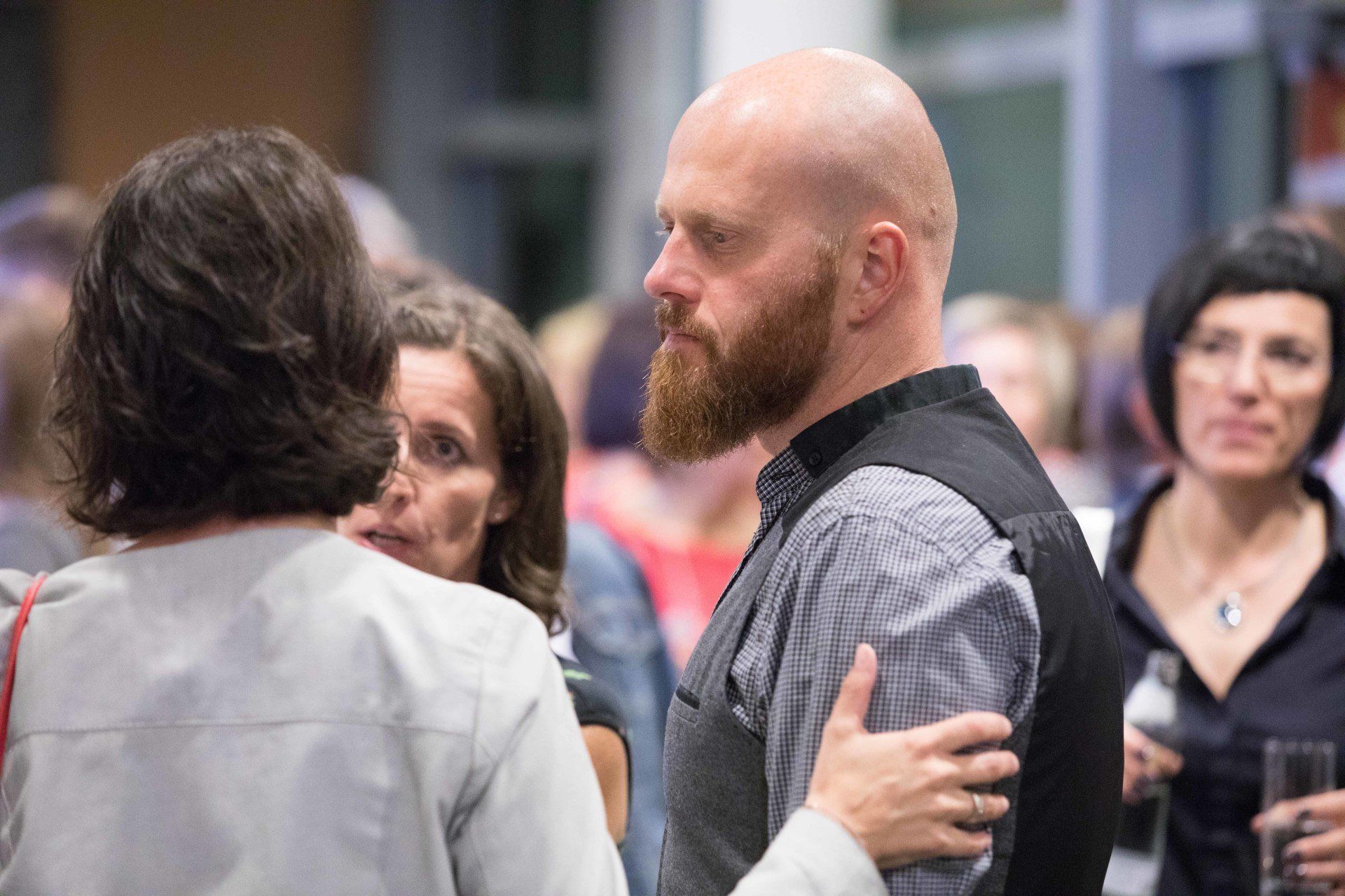 Ein Mann mit Bart spricht in einer Menschenmenge mit einer Frau.