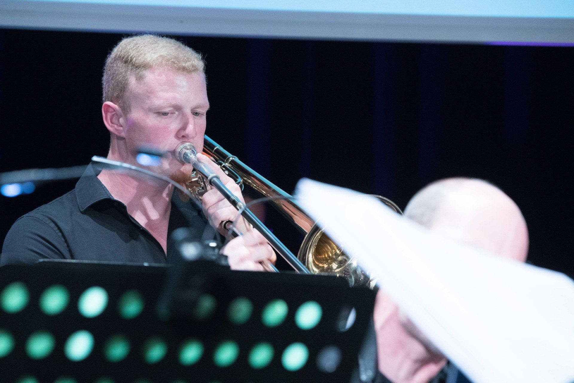 Ein Mann in einem schwarzen Hemd spielt auf einer Bühne Posaune.