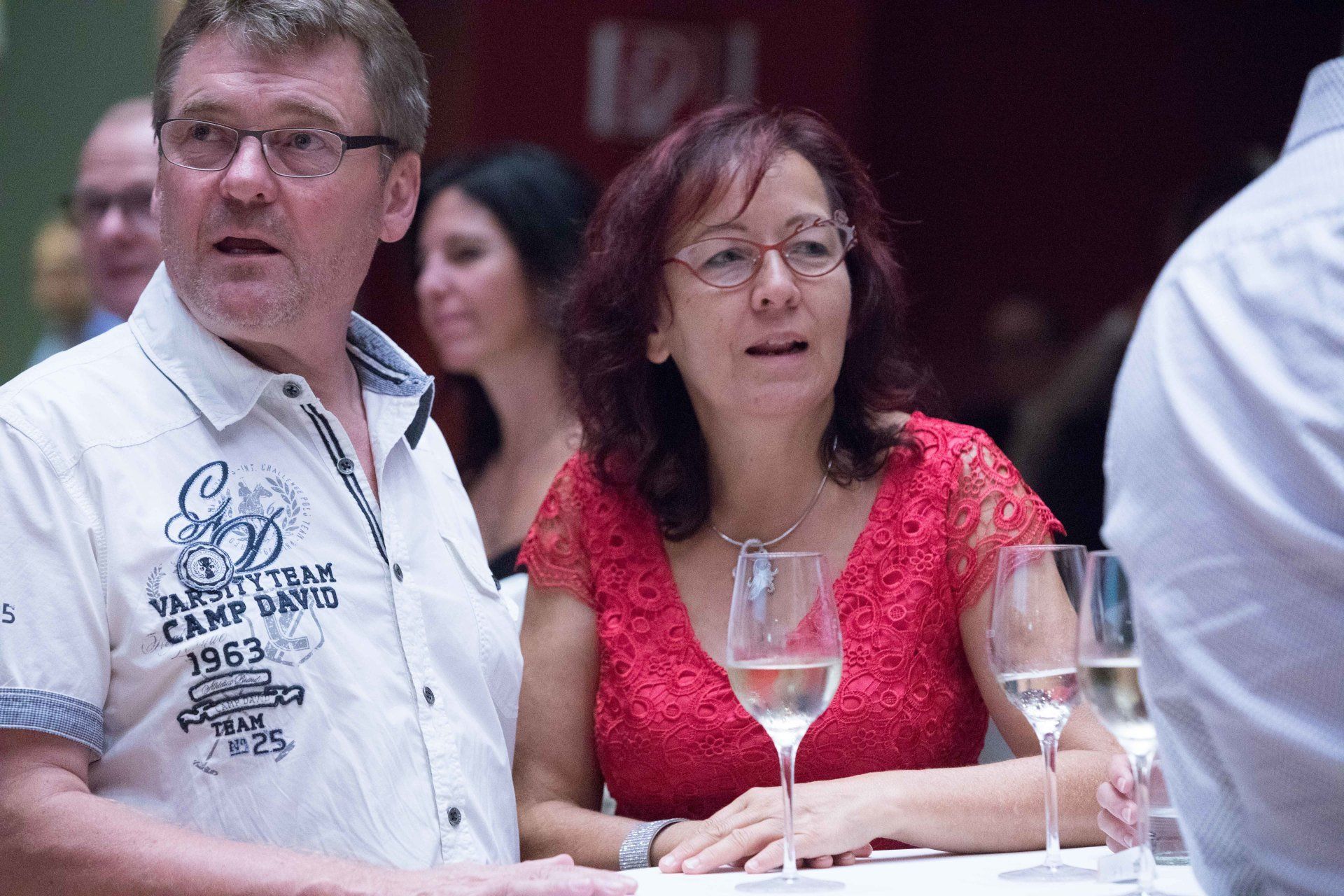 Ein Mann und eine Frau sitzen mit Weingläsern an einem Tisch.
