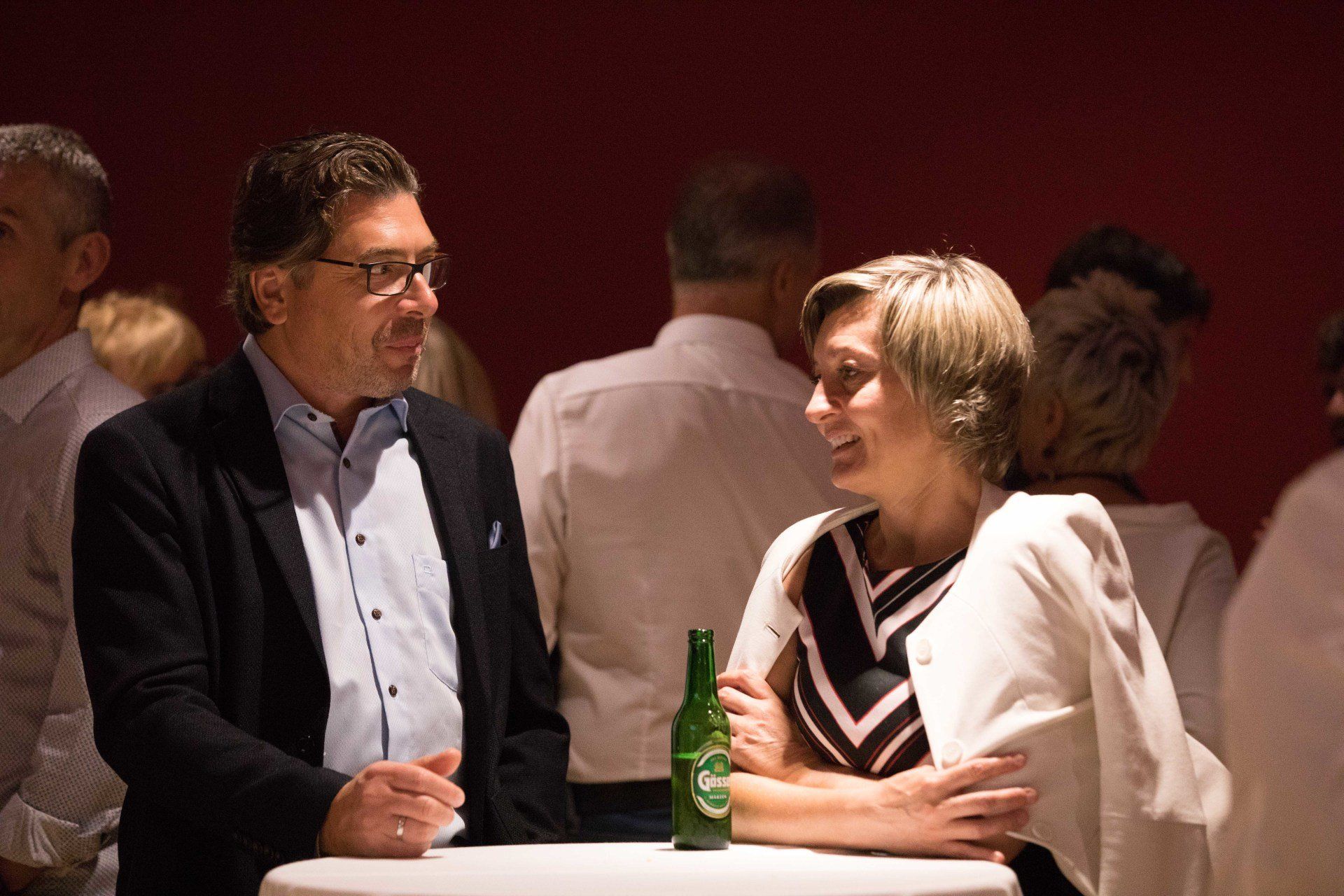 Ein Mann und eine Frau sitzen mit einer Flasche Bier an einem Tisch.