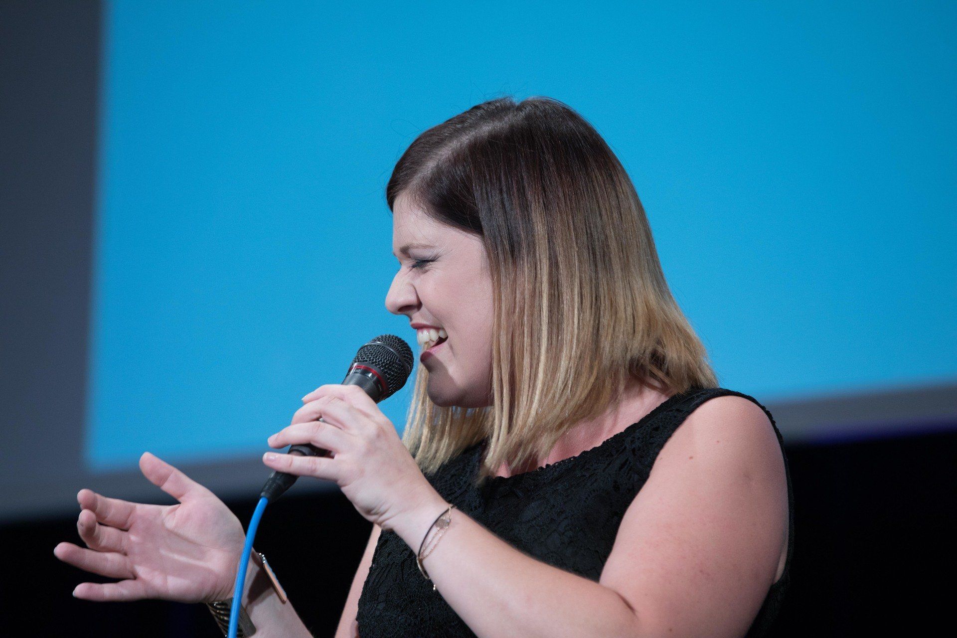 Eine Frau in einem schwarzen Kleid singt in ein Mikrofon.