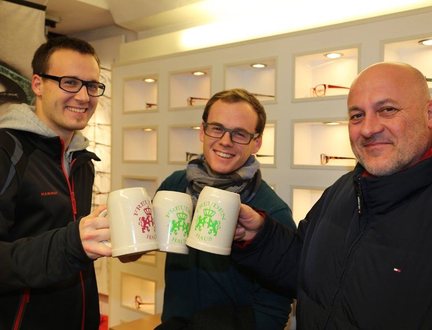 Drei Männer halten Tassen in den Händen und einer von ihnen trägt eine Brille