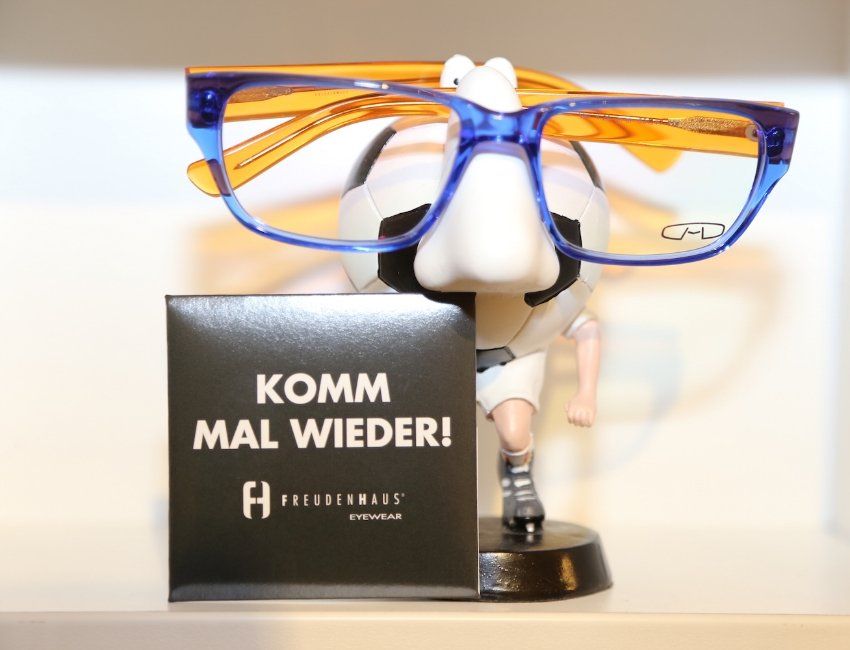 Eine Brille neben einem Schild mit der Aufschrift „Komm mal wieder“