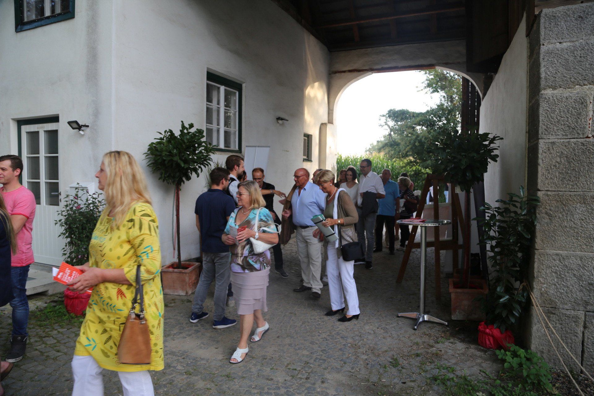 Eine Gruppe von Menschen steht vor einem Gebäude und unterhält sich.
