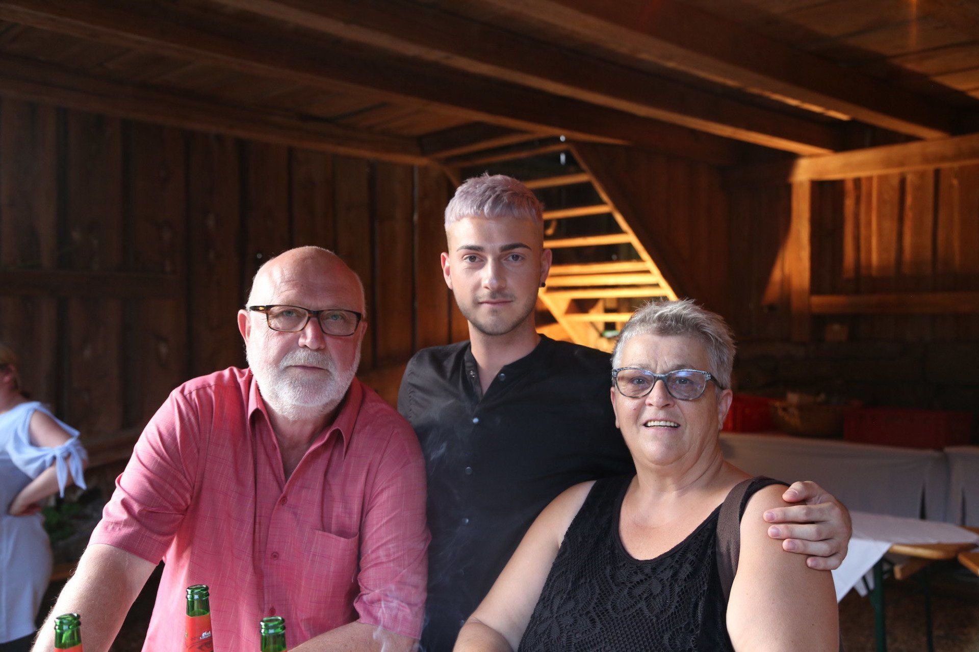 Ein Mann und zwei Frauen posieren in einem Raum für ein Foto.