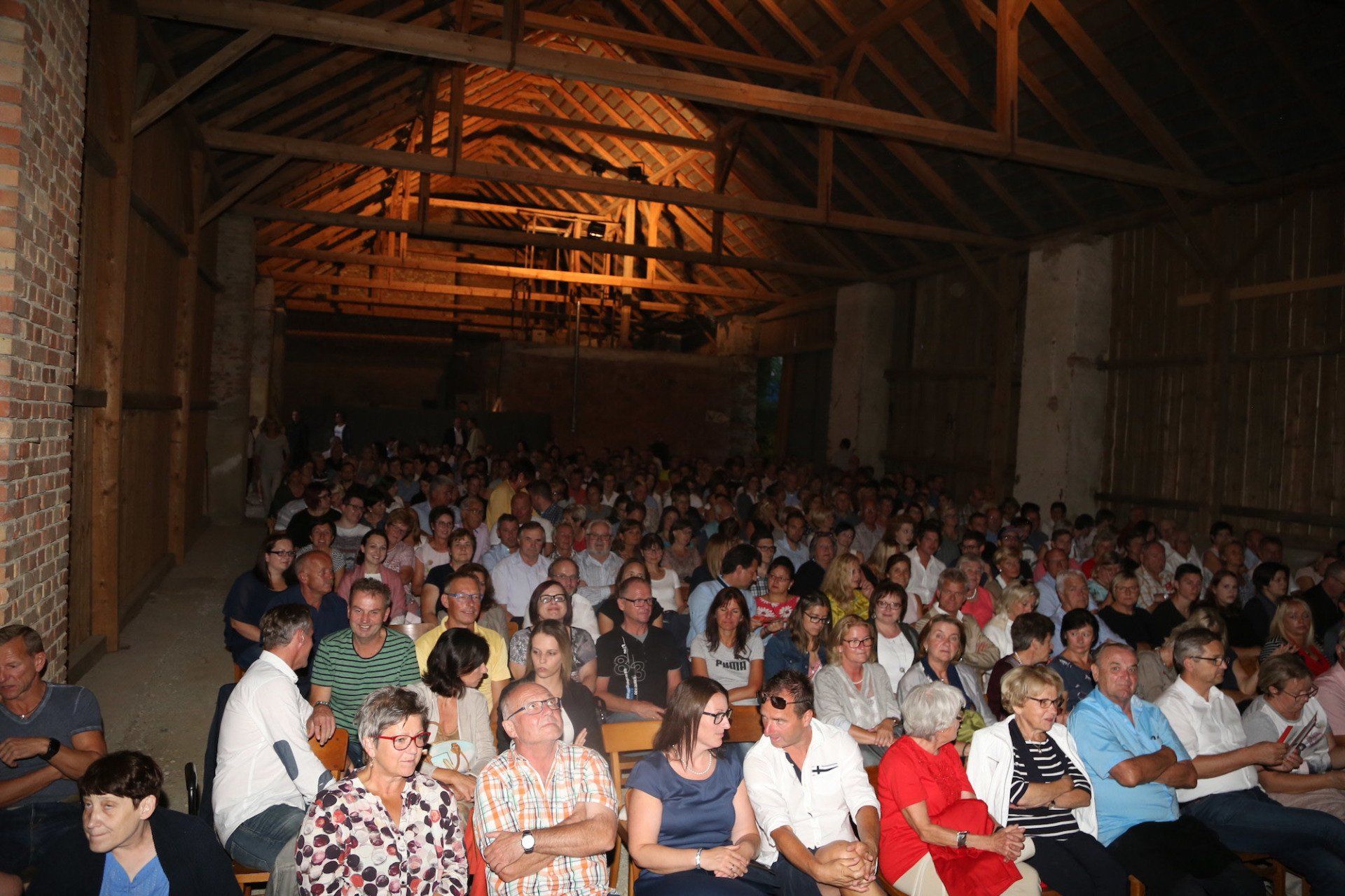 Eine große Gruppe von Menschen sitzt in einem dunklen Raum.