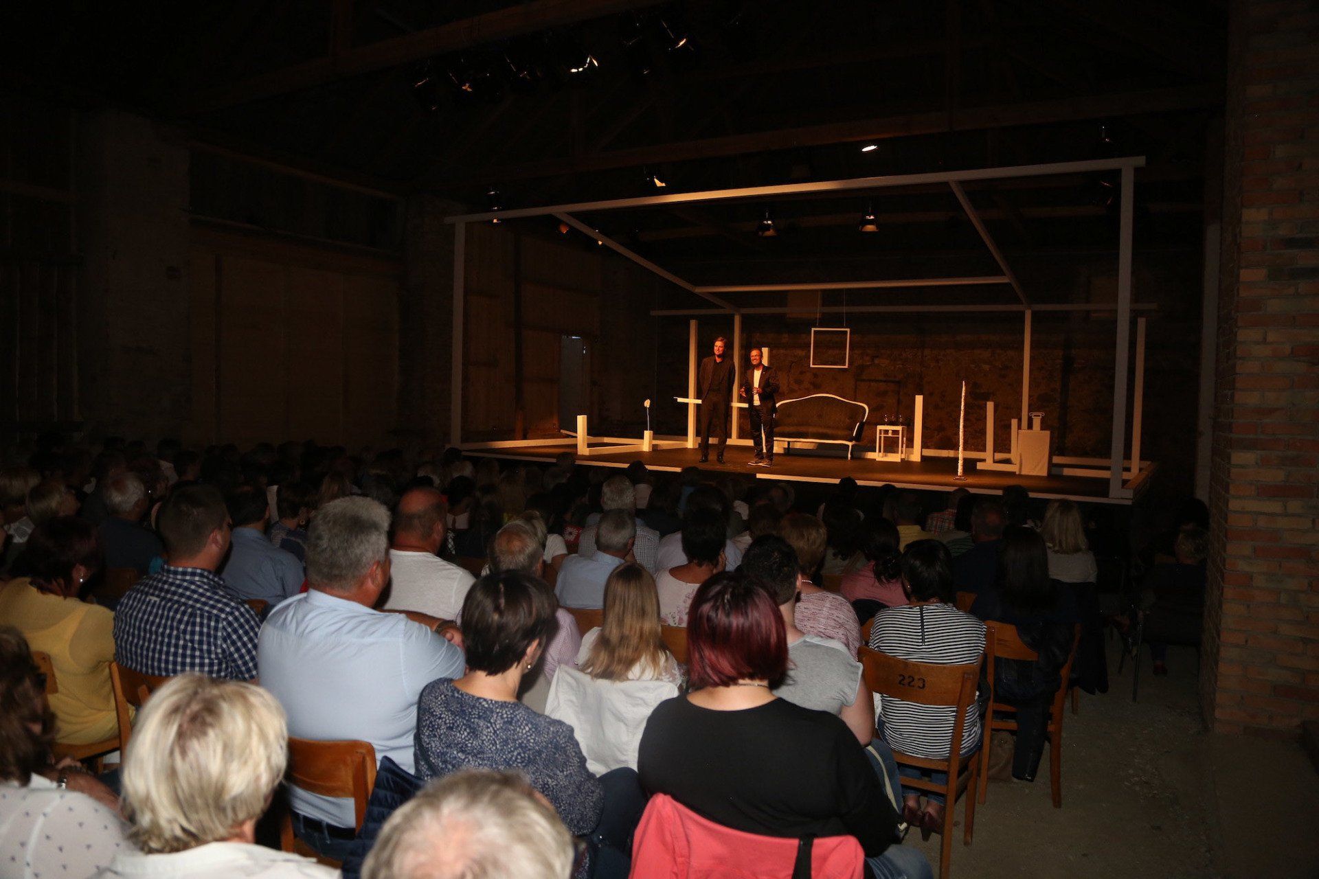 Eine große Gruppe von Menschen sitzt in einem Theater und sieht sich ein Theaterstück an.