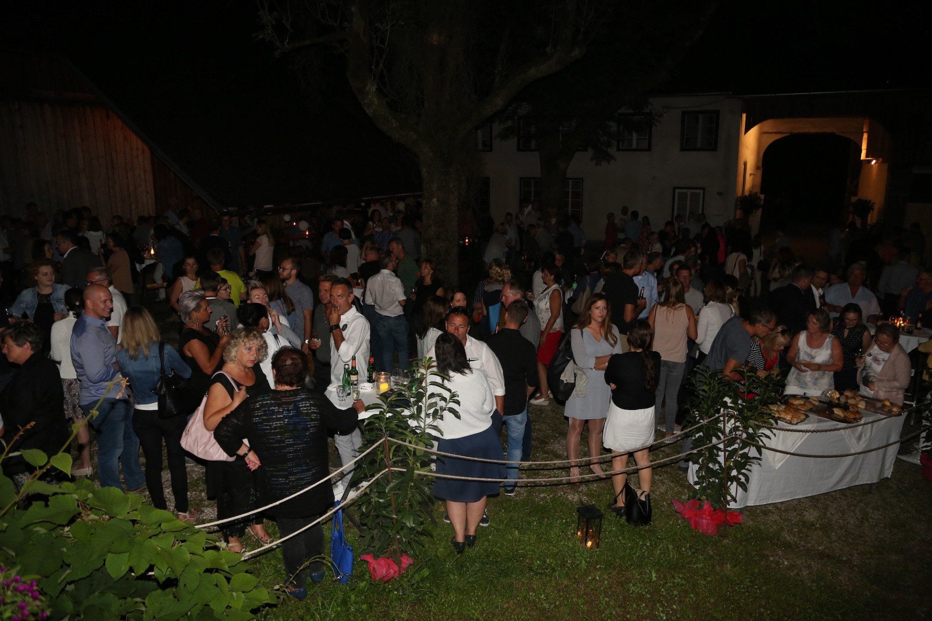 Eine große Gruppe von Menschen steht nachts um einen Tisch herum.