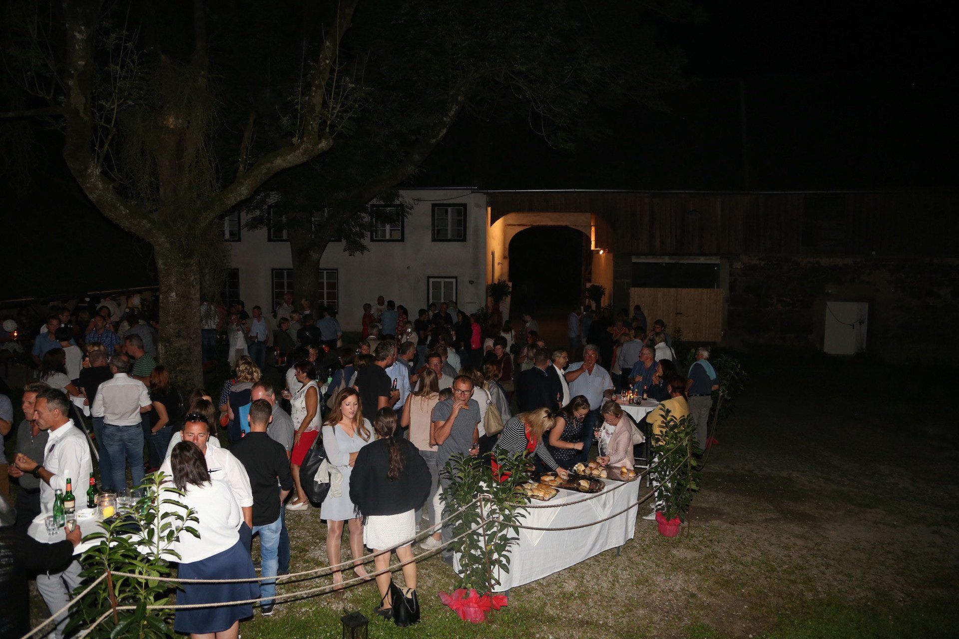 Eine große Gruppe von Menschen hat sich nachts vor einem Gebäude versammelt.