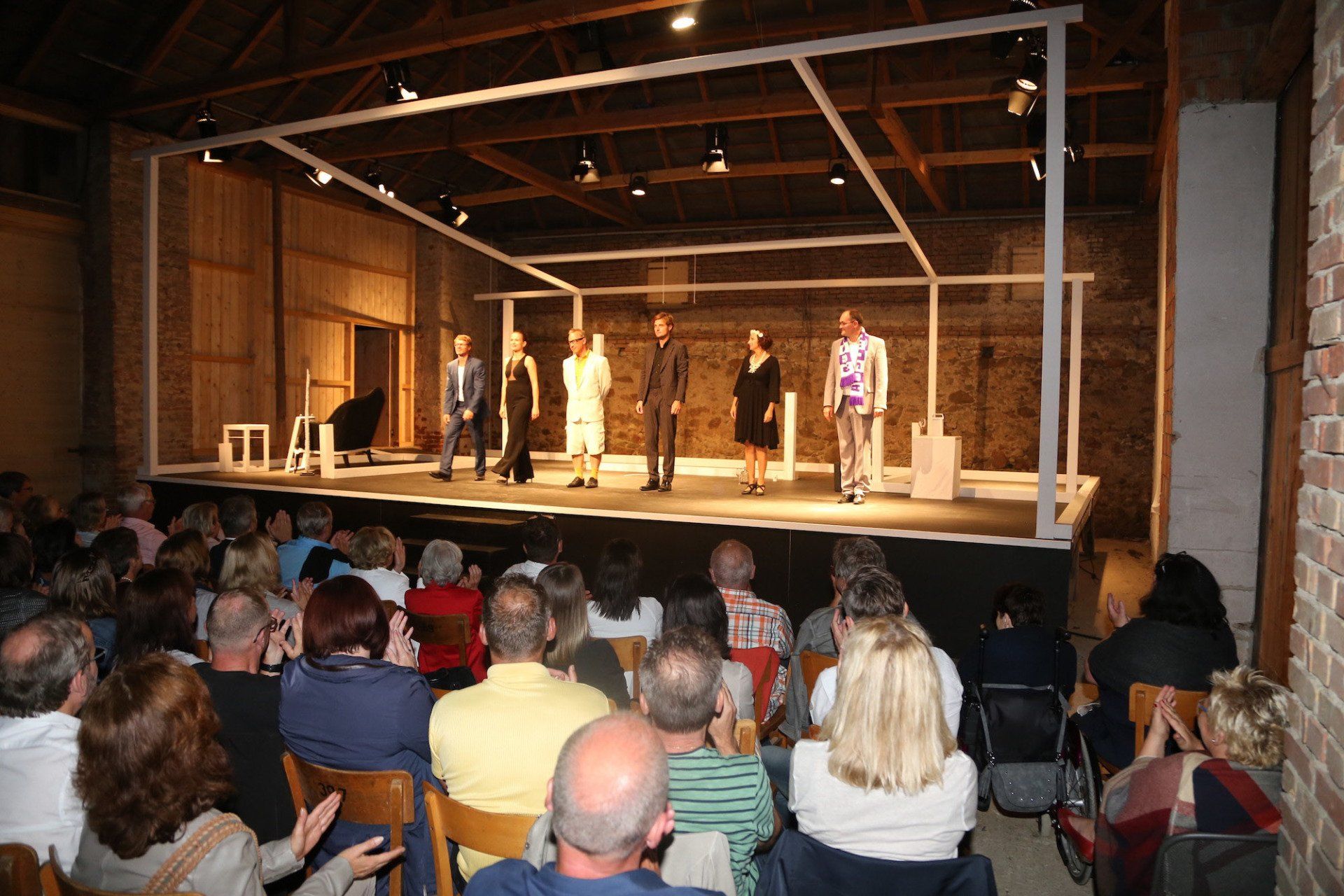 Eine Gruppe von Menschen sieht sich ein Theaterstück auf einer Bühne an