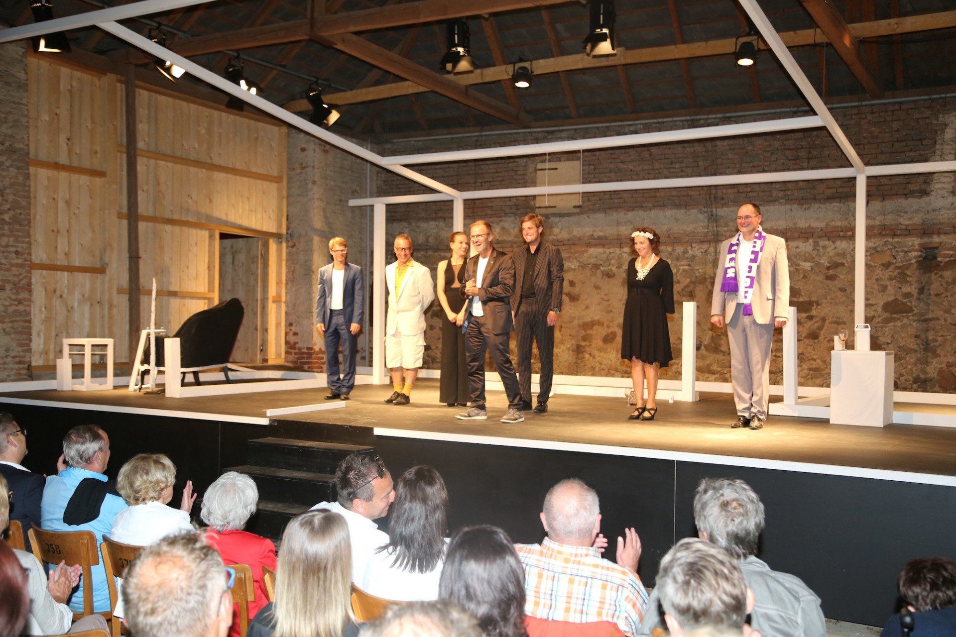 Eine Gruppe von Menschen steht vor einer Menschenmenge auf einer Bühne.