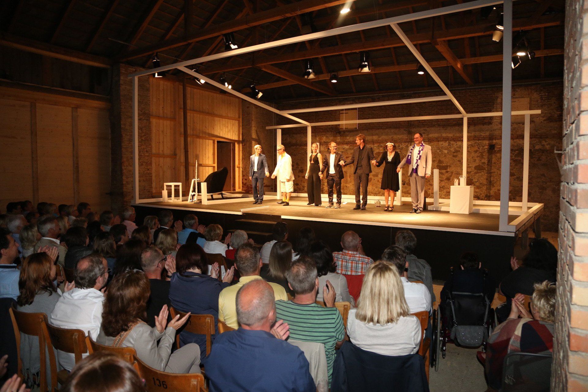 Eine Gruppe von Menschen sieht sich ein Theaterstück auf einer Bühne an.