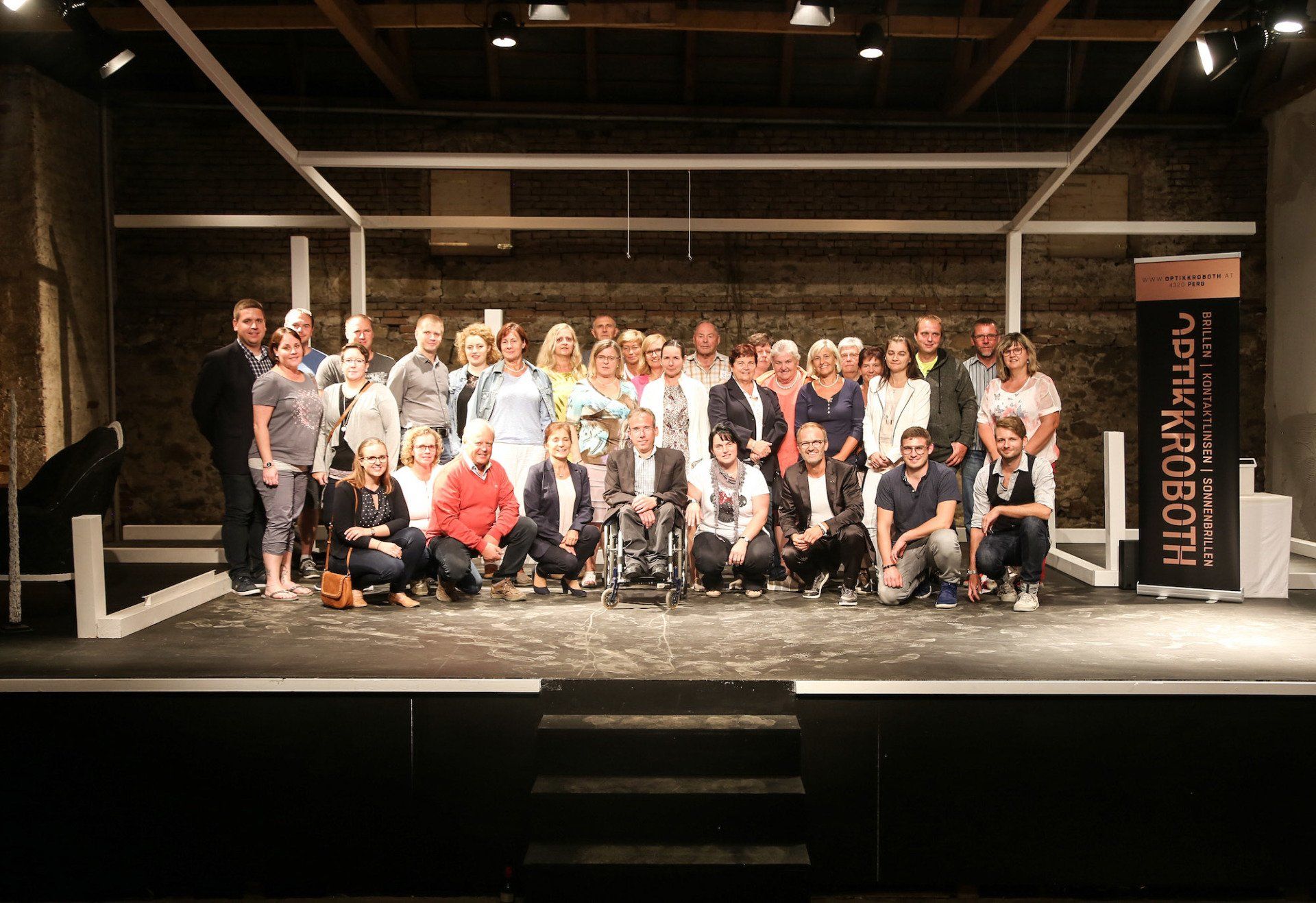 Eine Gruppe von Menschen posiert auf einer Bühne für ein Foto . Im Hintergrund ist eine Batterie zu sehen.