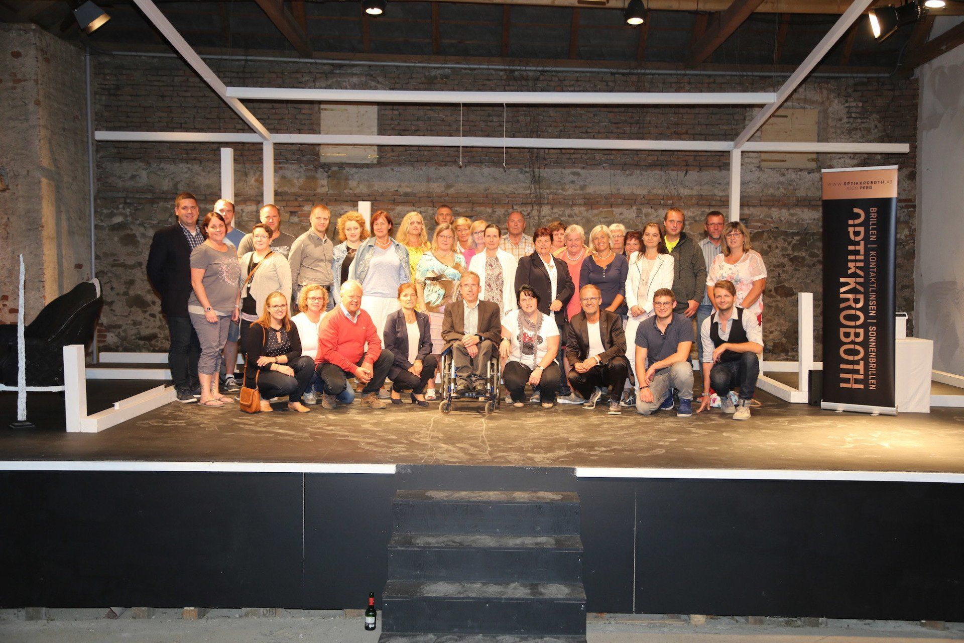 Eine Gruppe von Menschen posiert auf einer Bühne für ein Foto.