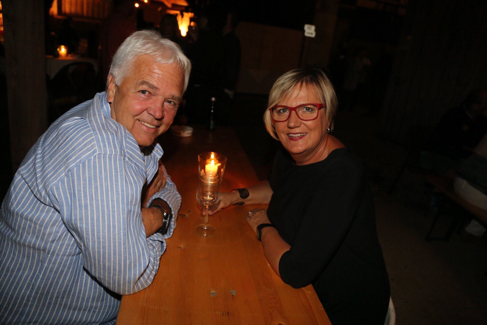 Ein Mann und eine Frau sitzen mit einer Kerze an einem Tisch.