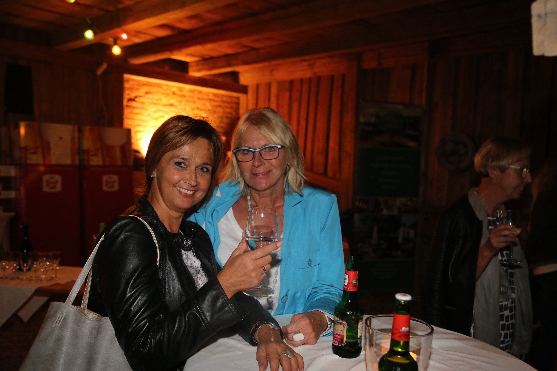 Zwei Frauen sitzen an einem Tisch und halten Weingläser in der Hand.