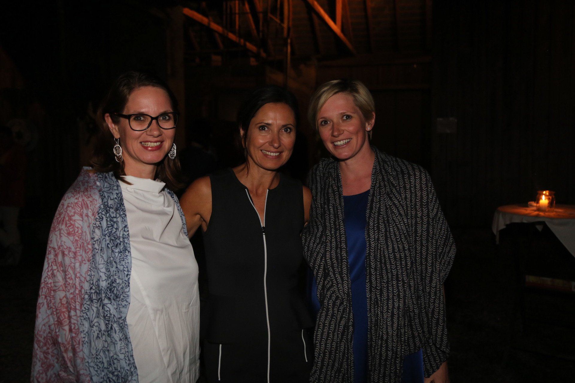 Drei Frauen posieren in einem dunklen Raum zusammen für ein Foto.
