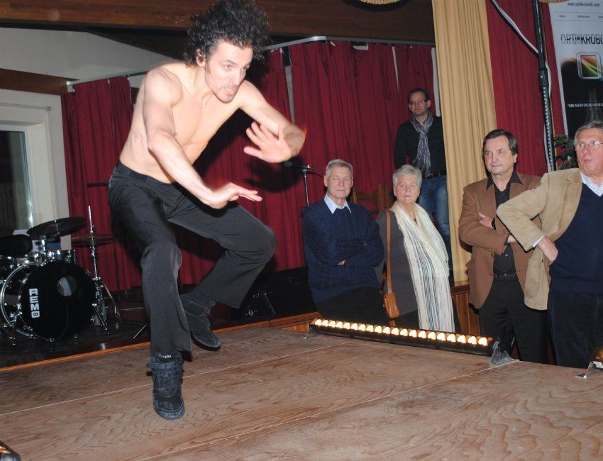 Ein Mann ohne Hemd tanzt auf einer Bühne vor einer Besetzungstrommel