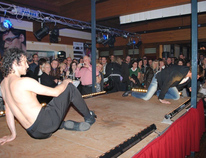 Ein Mann ohne Hemd steht auf einer Bühne vor einer Menschenmenge