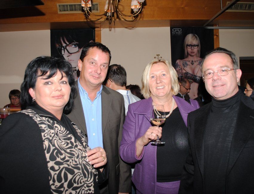 Eine Gruppe von Menschen, die für ein Foto posieren, wobei eine Frau ein Glas Wein hält