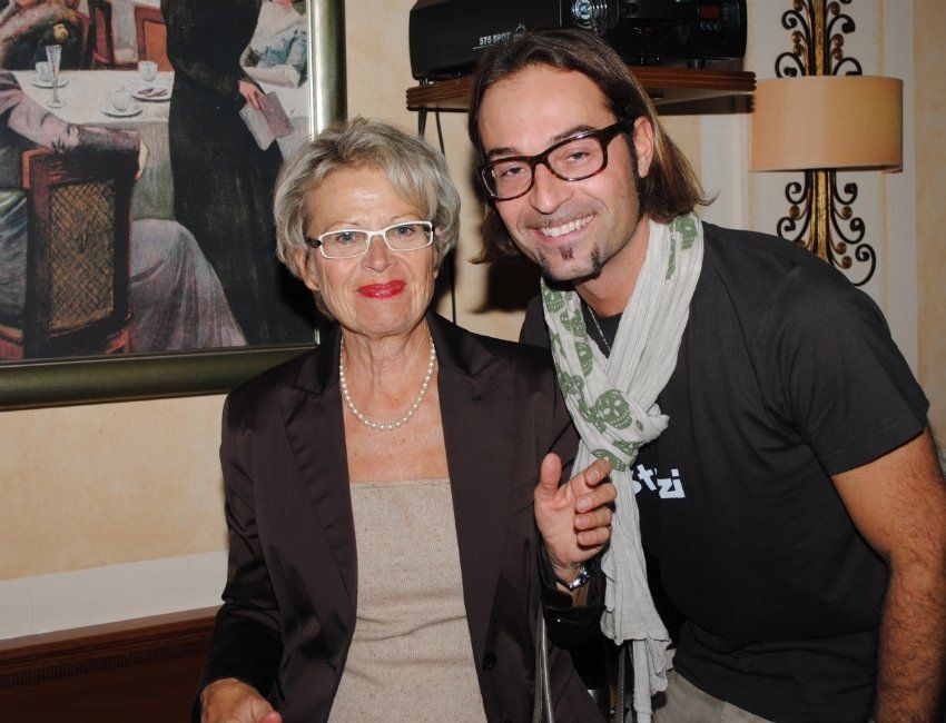 Ein Mann und eine Frau posieren für ein Foto, wobei der Mann ein T-Shirt mit der Aufschrift „nzi“ trägt
