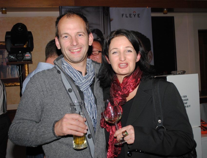 Ein Mann und eine Frau posieren für ein Foto vor einem Schild mit der Aufschrift „Fleye“