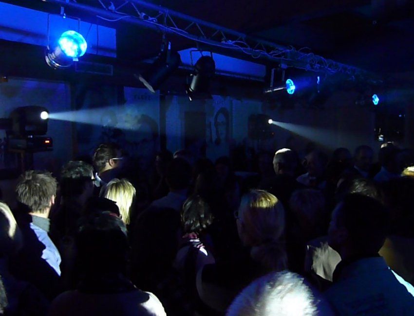 Eine Menschenmenge versammelt sich in einem dunklen Raum mit blauem Licht