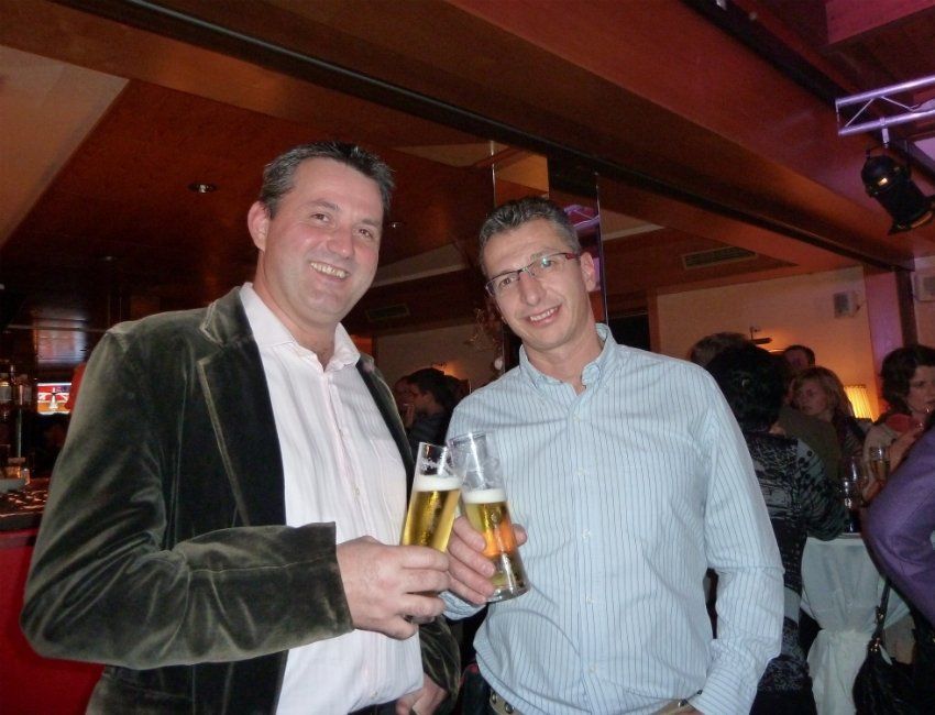 Zwei Männer stehen nebeneinander und halten Gläser mit Bier