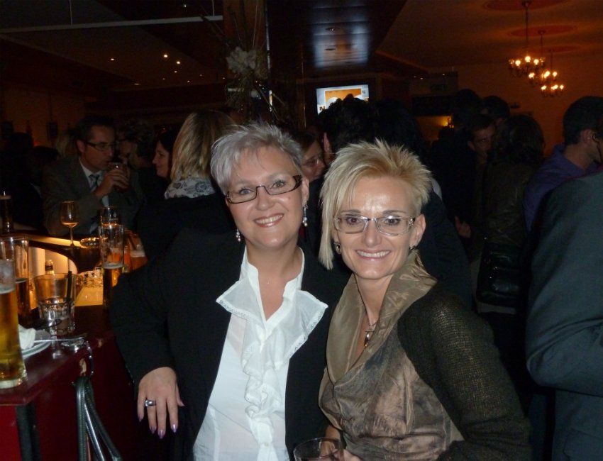 Zwei Frauen posieren für ein Foto in einem überfüllten Raum