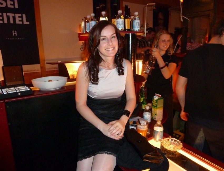 Eine Frau sitzt vor einem Schild mit der Aufschrift „sei eitel“