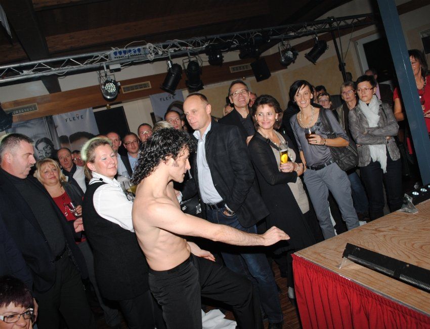 Ein Mann ohne Hemd tanzt vor einer Menschenmenge