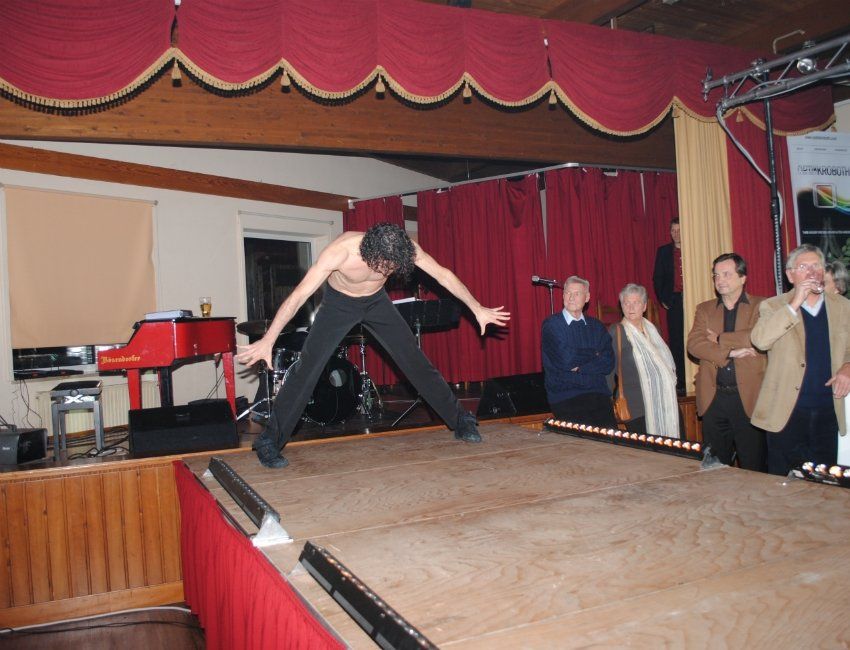 Ein Mann ohne Hemd springt auf einer Bühne in die Luft