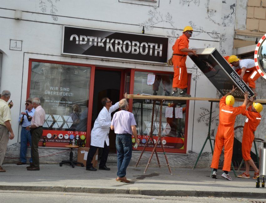 Eine Gruppe von Männern arbeitet vor einem Geschäft namens Optik Kroboth