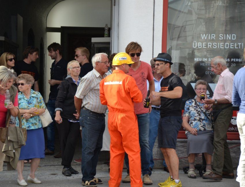 Eine Gruppe von Menschen steht vor einem Fenster mit der Aufschrift „Wir sind übersiedelt“