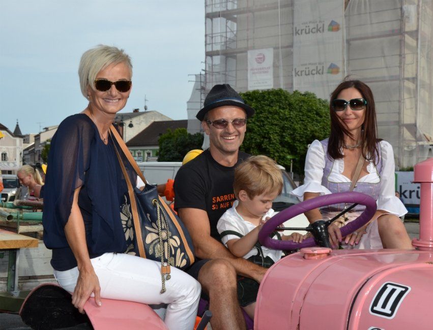 Eine Gruppe von Menschen sitzt auf einem rosa Traktor.