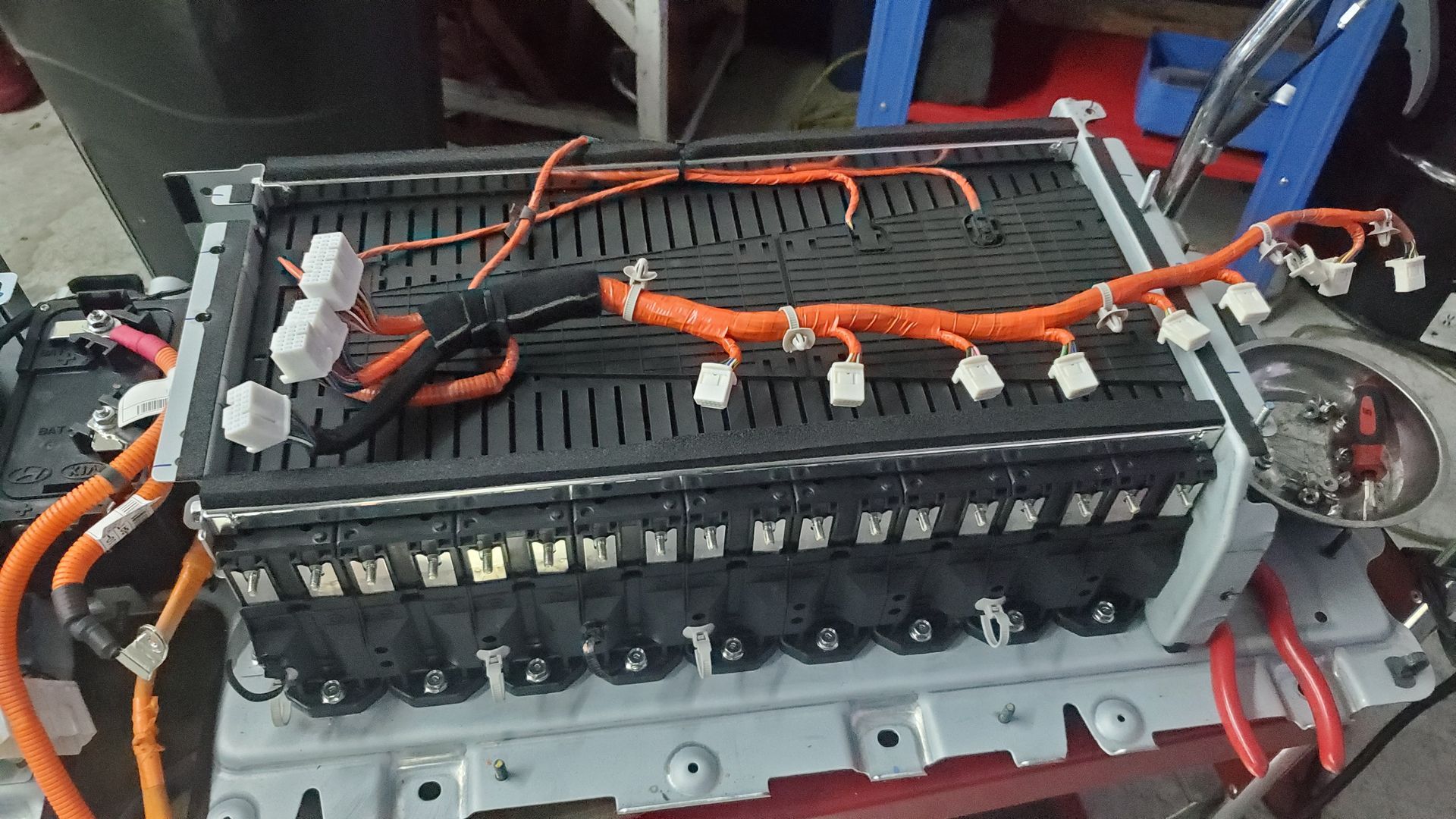 Battery pack with orange wiring inside an open electric vehicle compartment