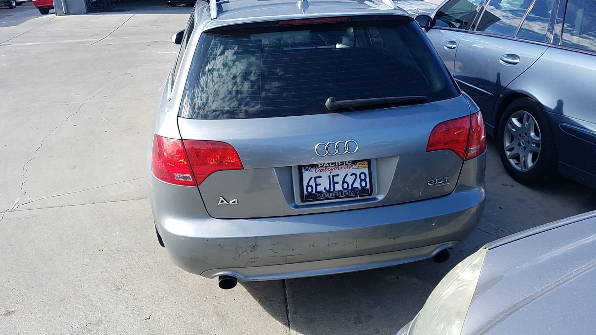Rear view of a gray SUV parked beside another car in a parking lot, showing a visible license plate.
