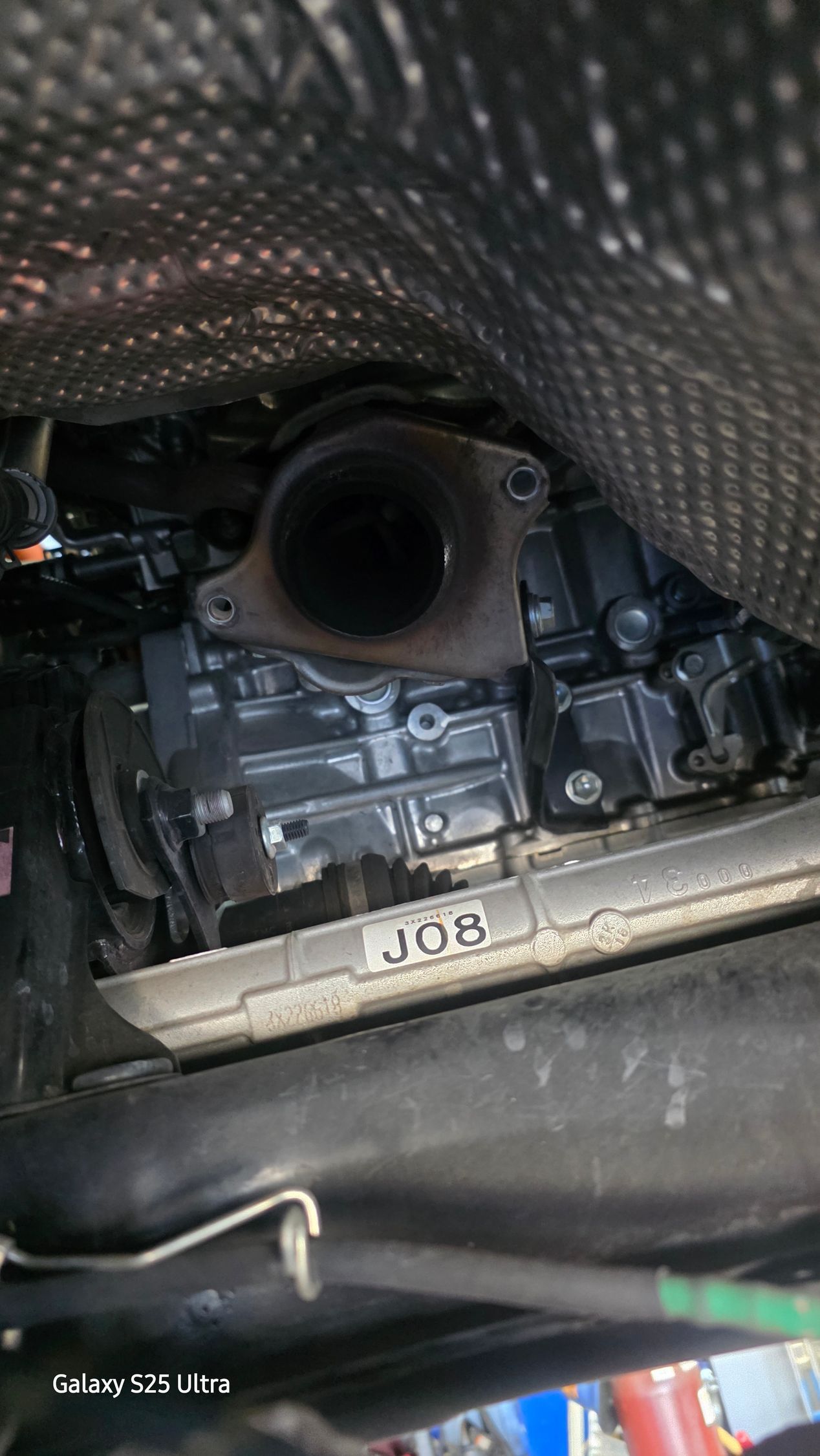 Close-up of a car engine bay with a large intake pipe and carbon-fiber-look cover.