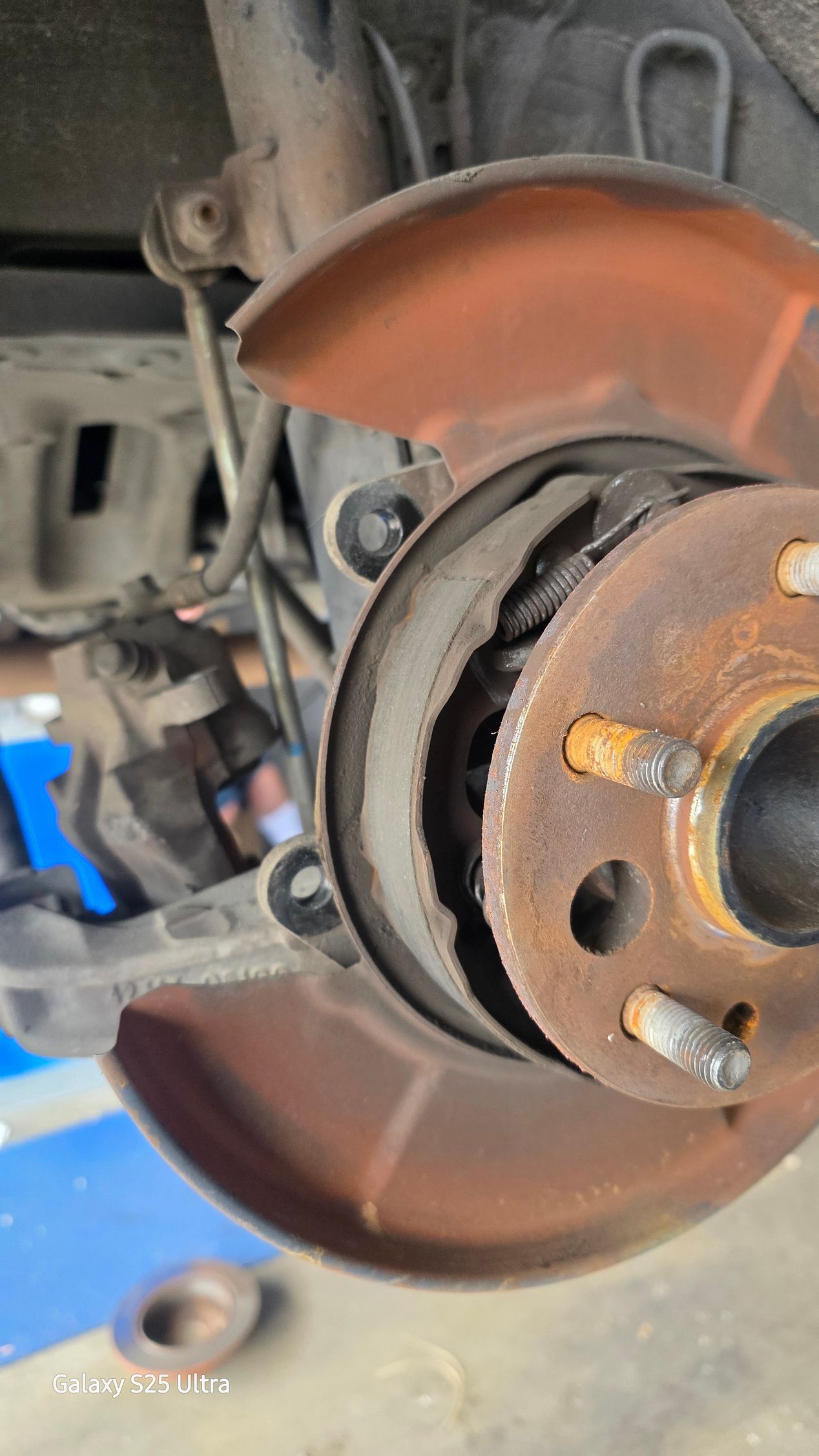 Close-up of a car wheel hub and brake rotor with rust and dust on a lifted vehicle