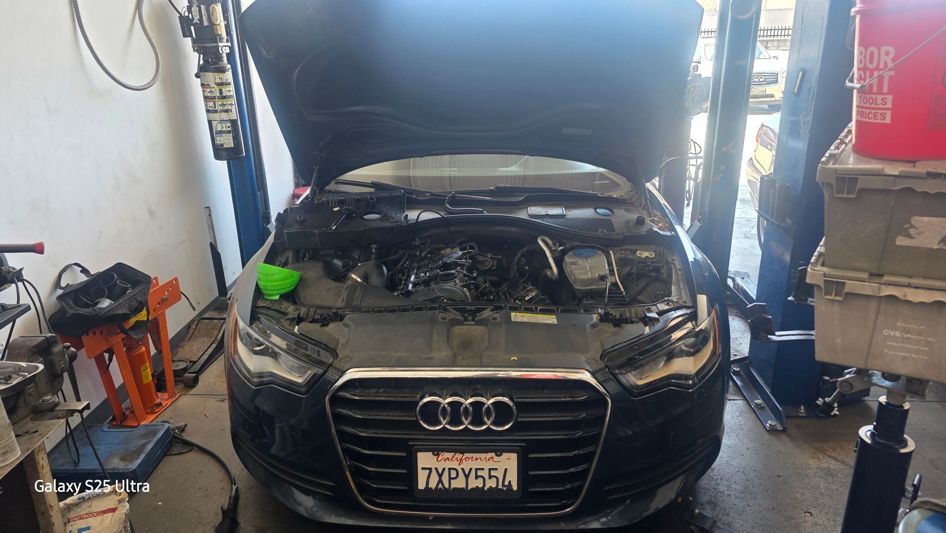 Black Audi in a garage with hood open, showing the engine bay during repair