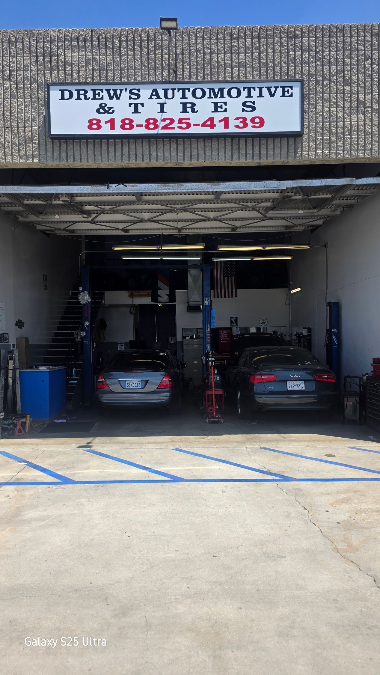Drew’s Automotive garage entrance with two cars inside and a sign above the service bays.