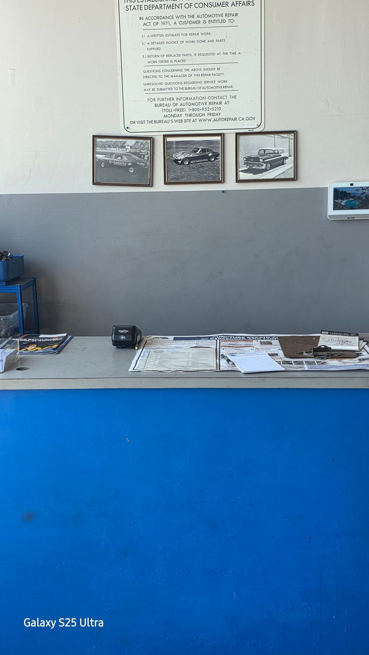 Blue front counter with brochures and framed certificates on a gray wall behind it.