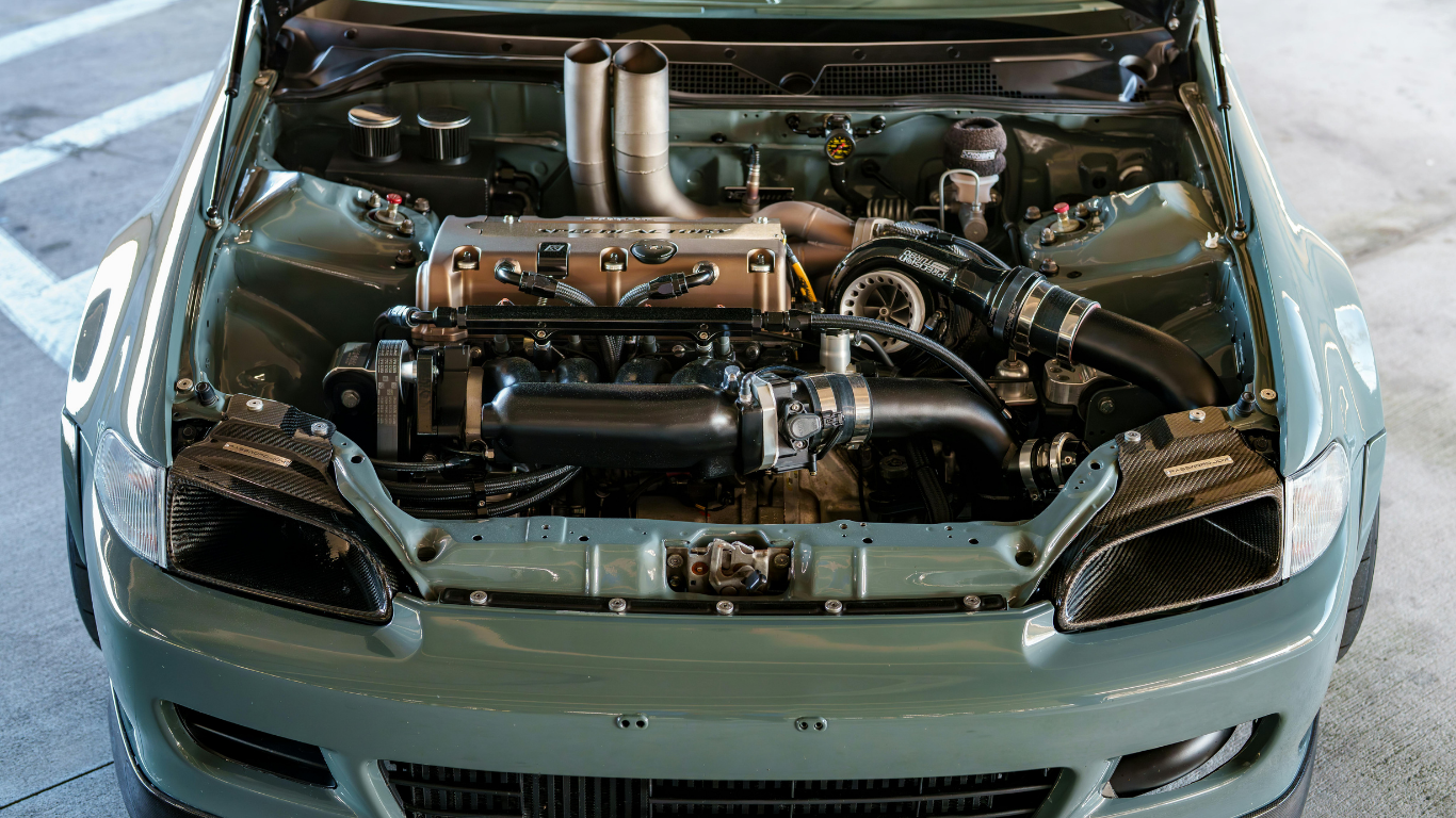 Modified car with exposed engine bay, front view in a garage or workshop.